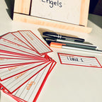 Set of flashcards with writing on a table with pens and a wooden frame.